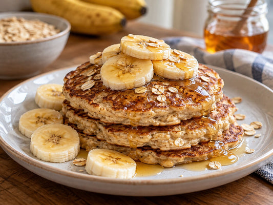 A stack of banana and oat pancakes with banana slices and honey