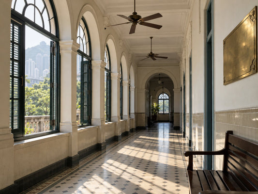 A colonial-era hospital corridor with arched windows, a tiled floor and a brass plaque