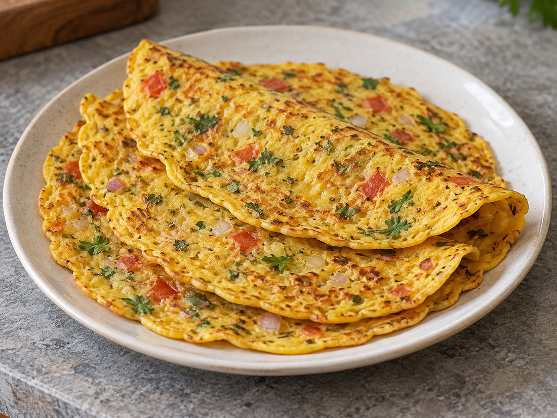 Illustrative golden besan chilla with onion, tomato and herbs.