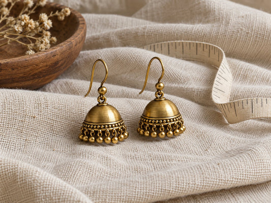 Illustrative bell-shaped jhumka earrings on plain fabric.
