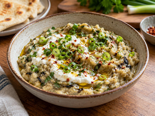 Roasted aubergine mixed with yoghurt and spring onions in a shallow bowl
