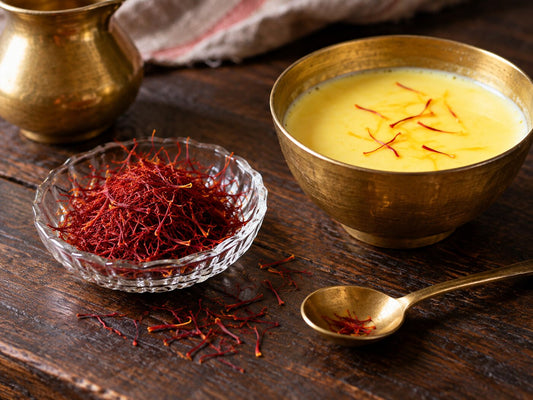 Red saffron threads in a small dish and a few steeping in warm milk